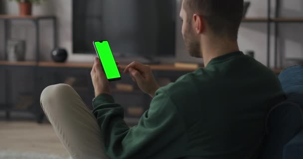 L'uomo sta giocando ai videogiochi nello smartphone, premendo il pulsante sullo schermo del sensore e vincere, schermo verde sul cellulare, felice e gioioso — Video Stock