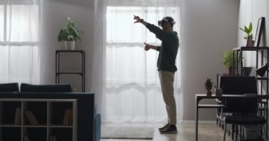 Adam fotoğrafları ve resimleri HMD cihazının dairesinde, el hareketleriyle zumluyor, oturma odasında tek başına duruyor.
