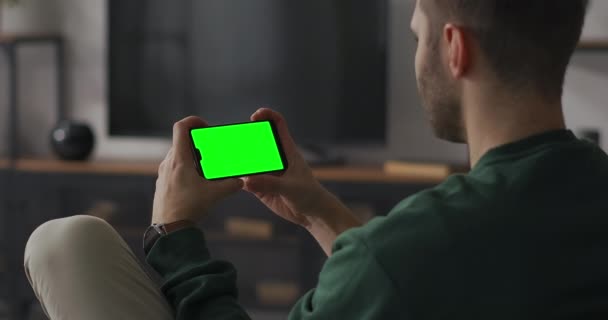 Man is viewing on smartphones with green screen, listening and waving head, communicating by video call and online chat — Stock Video