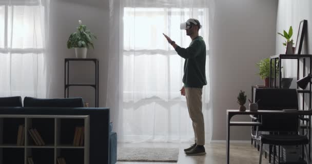 Hombre adulto está utilizando la realidad virtual para la educación, usando la pantalla montada en la cabeza y deslizando la pantalla a mano en la habitación — Vídeo de stock