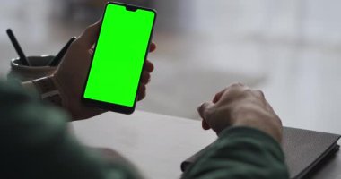 Çalışan bir adamın ellerinde krom anahtarı olan akıllı telefon, ellerin yakın görüntüsü, video çağrısı ile çevrimiçi iletişim.