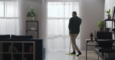 Komik adam temizlik sırasında şarkı söylüyor, kulaklıkla müzik dinliyor, dans ediyor.