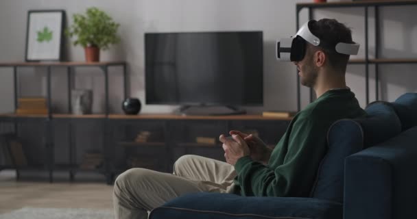 Adulto hombre está jugando juego de ordenador moderno, utilizando la pantalla montada en la cabeza y joystick, tecnología de realidad virtual para la diversión — Vídeo de stock