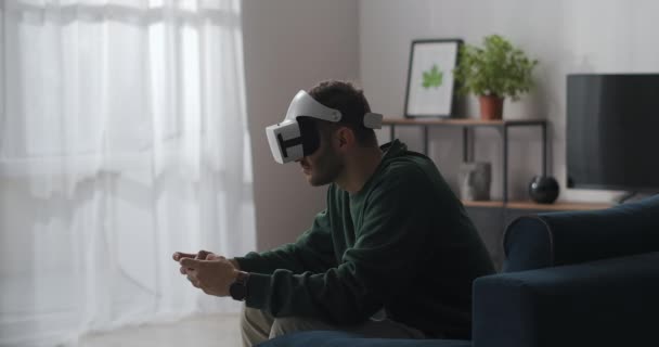 Uomo adulto sta giocando giochi per computer utilizzando vr occhiali e joystick, seduto da solo a casa, tecnologia di realtà virtuale — Video Stock