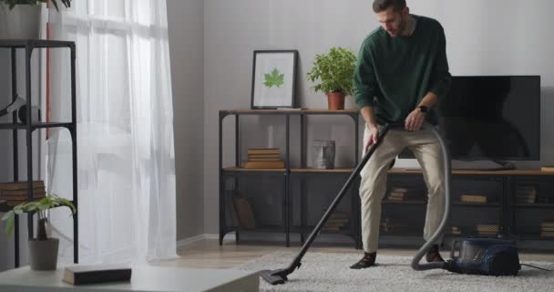 Czyszczenie dywanu odkurzaczem, mąż tańczy i unosi się, pomaga w domu, bawi się — Wideo stockowe