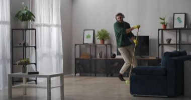 Neşeli bekar evde temizlik yaparken, yerleri yıkarken, paspasla dans ederken, kulaklıkla müzik dinlerken eğleniyor.