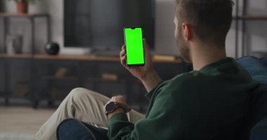 Adam akıllı telefondan müşteriyle görüntülü konuşma yapıyor, evden uzaktan çalışıyor, yeşil ekran teknolojisi.