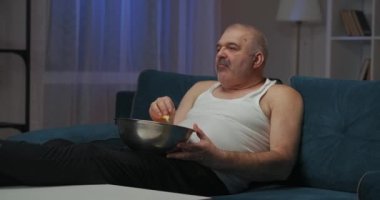 Yaşlı adam işteki uzun bir günün ardından sessizce televizyonun önünde oturup patlamış mısır yiyor. Gece geç saatlerde yatak odasında televizyon, işten sonra dinlenen bir adam, TV 'de film seyrediyor. Kapat.