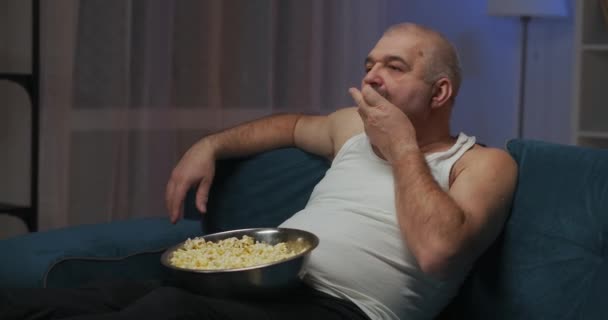 L'uomo mastica i popcorn. Gli mette del grano in bocca con la mano sinistra.. — Video Stock