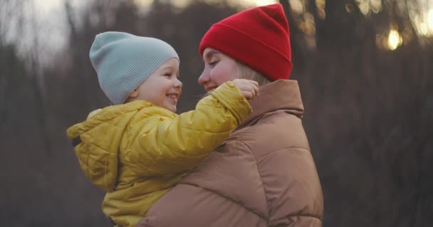 Maman tient son petit fils dans ses bras. Regardez-le tendrement, puis tourne la tête et regarde la caméra et sourit. Au ralenti. Plan moyen. — Video