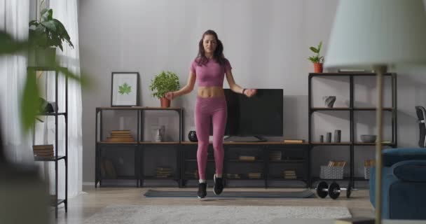 Correr en el lugar de ejercicio en casa, mujer delgada está usando ropa deportiva para la aptitud está entrenando en el apartamento solo — Vídeo de stock