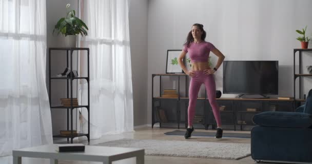 Hemmaträning på självisolering och nedstängning, hålla sig i form, ung kvinna gör aerobics — Stockvideo