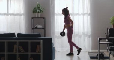 Atletik kadın ağırlık egzersizleri yapıyor, evde tek başına antrenman yapıyor, öne eğiliyor ve bacağını kaldırıyor, ince kadın figürü.
