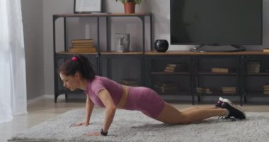 Dairesinde şınav çeken genç, sportif bir kadın sabahları odasında tek başına antrenman yapıyor. İnce vücudunu formda tutuyor.