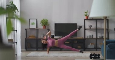 Sportif bayan oturma odasında bacak kasları, formda kalmak için ev eğitimi ve iyi hissetmek için egzersiz yapıyor.