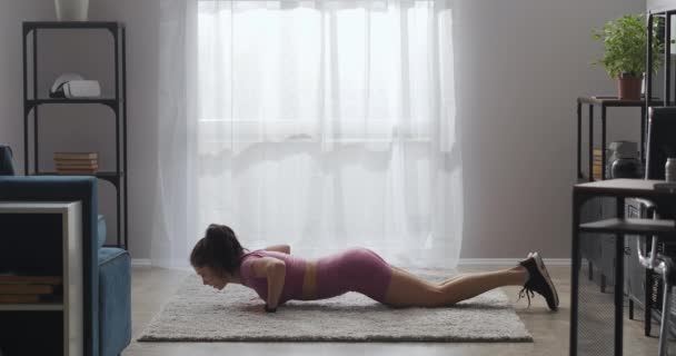 Femme sportive fait push-ups dans le salon, séance d'entraînement à la maison le week-end, garder la forme et une bonne condition physique — Video