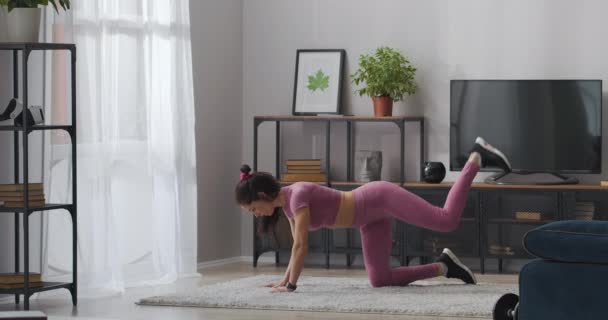 Home workout voor het verliezen van gewicht en fit te houden, atletische vrouw tilt benen omhoog voor een goede lichaamsvorm — Stockvideo