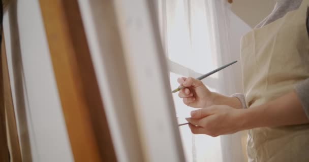 Handen van vrouwelijke kunstenaar tijdens het werk in de studio, vrouw tekent beeld op doek, details opgenomen in workshop — Stockvideo