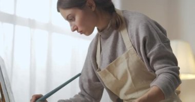 Öğrenci kadın fırça ve boyayla resim çiziyor, portre ve detaylar, yetenekli ve ilham verici kişi