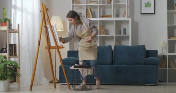 Peinture femme dans l'appartement le week-end, passe-temps créatif de l'artiste féminine, travail dans le home studio, dessin sur chevalet, pleine longueur — Video