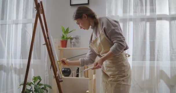 Favoriete tijdverdrijf van jonge getalenteerde vrouw in het weekend, vrouwelijke kunstenaar is schilderij op doek, het aanbrengen van olieverf met een penseel — Stockvideo