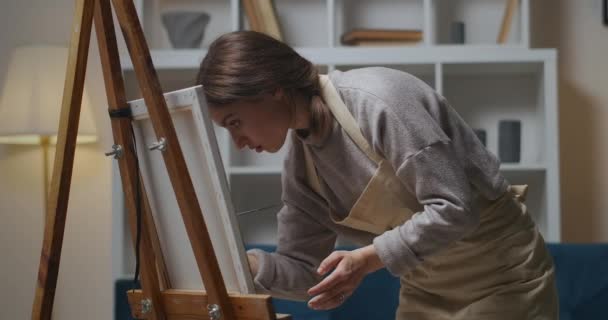 Noche tranquila en casa, mujer está pintando cuadro por tintes al óleo en el apartamento, aplicando colores sobre lienzo, artista profesional — Vídeos de Stock