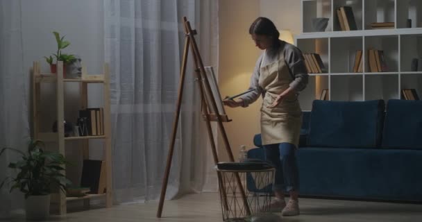 Jeune femme fait passe-temps créatif le soir, dessin image sur toile, en utilisant le salon comme atelier de travail — Video