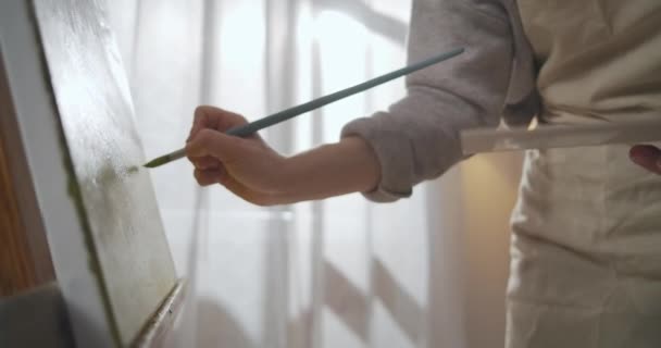 Schilderen vrouwelijke kunstenaar in workshop overdag, het toepassen van kleuren op doek, closeup view, hobby en favoriete tijdverdrijf — Stockvideo