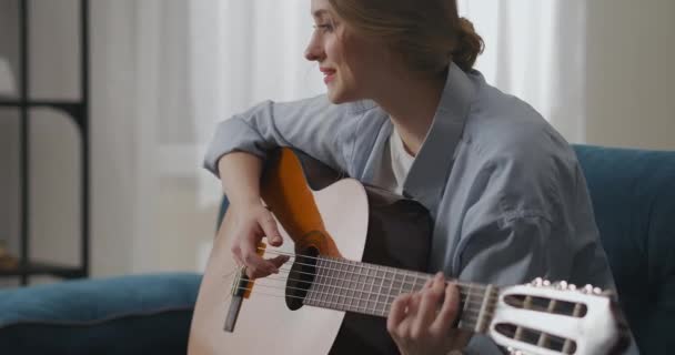 여자 기타리스트가 집에서 컴퓨터 웹 카메라 앞에 앉아 기타를 치고 있습니다. 친구들을 위해 온라인 콘서트를 하고 있고, 인터넷을 통해 가정 공연을 하고 있습니다. — 비디오