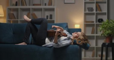 Düşünceli kadın, hüzünlü ve sıkıcı bir şekilde, akşamları rahat bir dairede, kanepede uzanıp hüzünlü bir şarkı çalıyor.