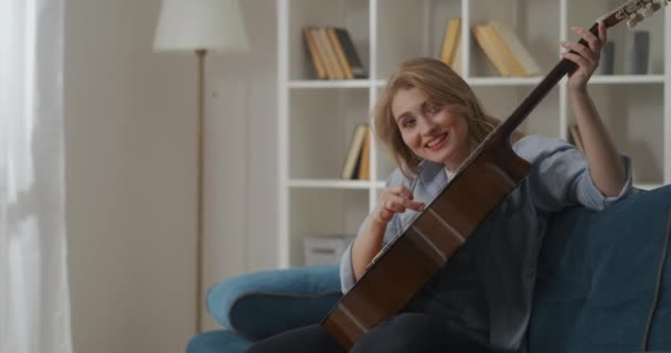 Divertente donna sta suonando la chitarra insolitamente e ridendo, sperimentare con strumento musicale e scherzo nei fine settimana — Video Stock