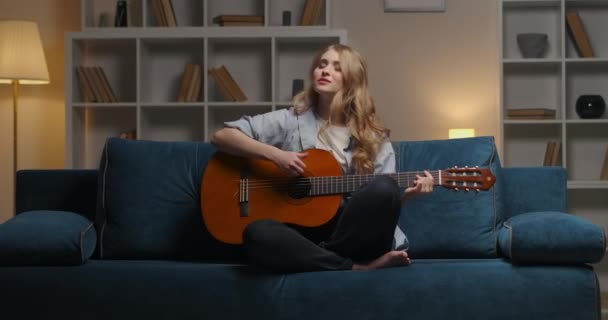 Vonzó érzelmi nő játszik kedvenc dal gitáron ül egyedül otthon este, közepes portré — Stock videók