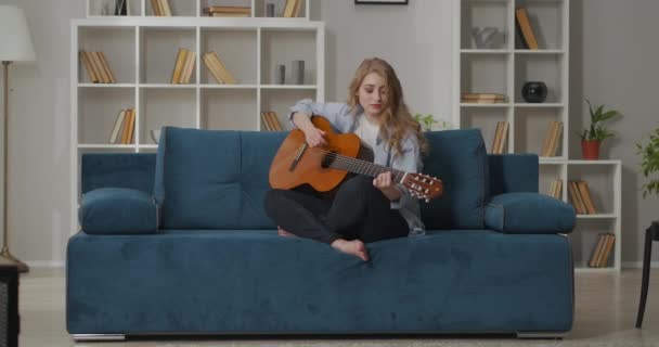 Attraktiv kvinna med gitarr tillbringar ledig tid hemma på helgen, spela musik och sjunga sång, koppla av på semester — Stockvideo