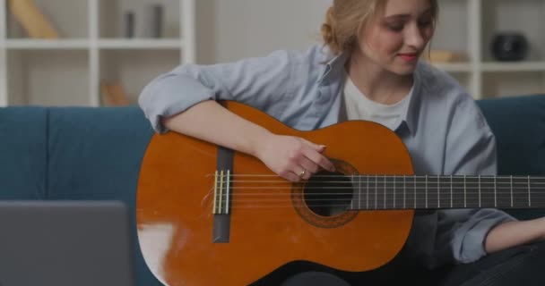 Joven músico principiante femenino está tocando la guitarra y agitando la cabeza para golpear, mujer sonriente en el apartamento en fin de semana — Vídeo de stock