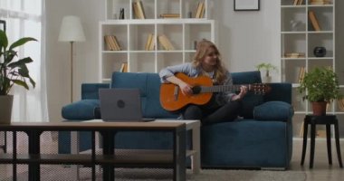 Güzel düşünceli kadın evde tek başına gitar çalıyor, hafta sonları evde vakit geçiriyor, müziği seviyor.