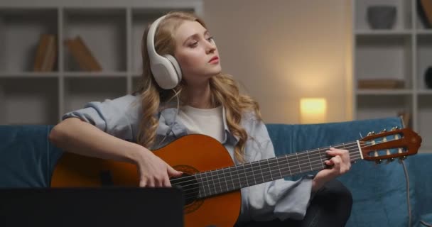 Inspirada mujer músico principiante está tocando la canción en la guitarra, disfrutando de la música y divertirse en casa por la noche, ensayando y componiendo melodía — Vídeo de stock