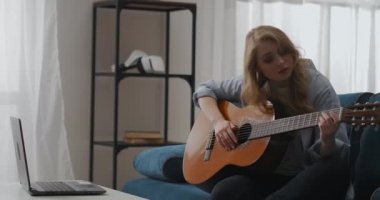 Çekici sarışın kadın gitar çalıyor, hafta sonları evde oturup müzik ve şarkı yazıyor.