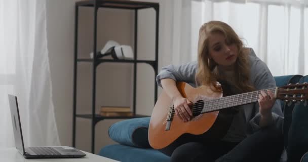 Charmant blond vrouw speelt gitaar, zitten thuis in het weekend, componeren muziek en lied — Stockvideo