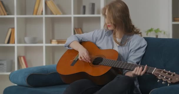 Mujer romántica y alegre está tocando la guitarra solo en casa, pasar tiempo libre en el apartamento con el instrumento musical favorito — Vídeos de Stock