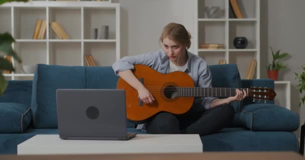 Ung kvinna tittar på video tutorial och spela gitarr hemma, utbildning online, kvinnlig nybörjare musiker — Stockvideo