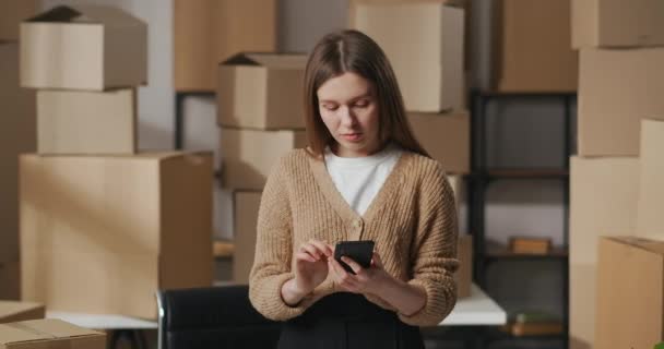 Smm manager kvinna kommunicerar i online chat i sociala nät med kunder, porträtt i lager med lådor, små företag — Stockvideo