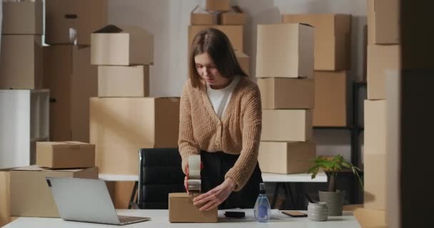 Mujer es caja de cinta adhesiva con orden de cliente, señora de negocios por cuenta propia en el almacén doméstico con cajas de cartón — Vídeos de Stock