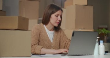 Kadın depo işçisi yeni kozmetik ve ev kimyasalları ürünleri üzerinde çalışıyor, internetten bilgi arıyor.