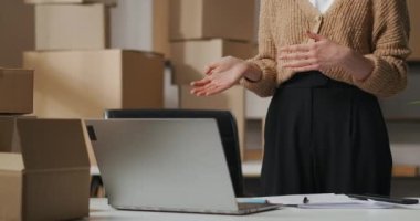 İş kadını, kozmetik ürünlerinin tedarikçisiyle bilgisayardaki görüntülü sohbet yoluyla iletişim kuruyor. Küçük ticaret şirketinin deposunda duruyor.