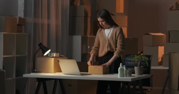 Γυναίκα ιδιοκτήτης της μικρής επιχείρησης εμπορίας καλλυντικών ξεπακετάρει το κιβώτιο με τα νέα αγαθά το βράδυ στην αποθήκη — Αρχείο Βίντεο
