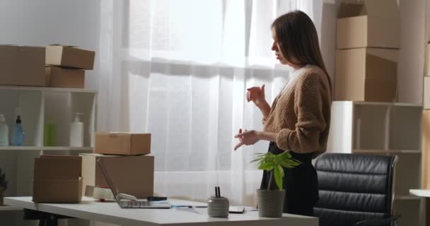 Femme propriétaire d'entreprise communique avec les employés et les partenaires par chat vidéo dans un carnet, portrait dans un petit entrepôt à la maison — Video