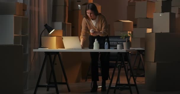 Podnikatelka pracuje sama ve svém domácím skladu s kosmetickými a domácími chemikáliemi v noci, učí se výrobky — Stock video