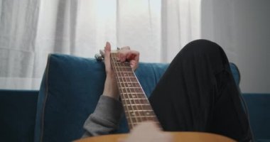 Gitarda akor çalan genç bir kadın. Gitarda tıngırdayan kız parmakları