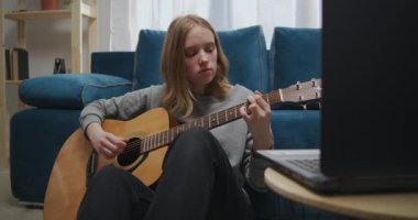 Kız dizüstü bilgisayarla gitar akorlarını inceliyor..