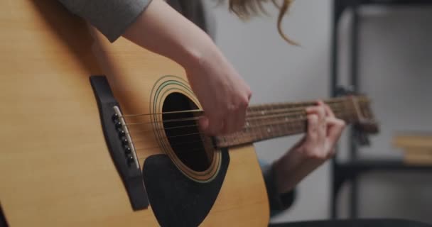 Meisje tiener linkerhand speelt de gitaar in haar kamer met witte muren. Close-up opname. — Stockvideo